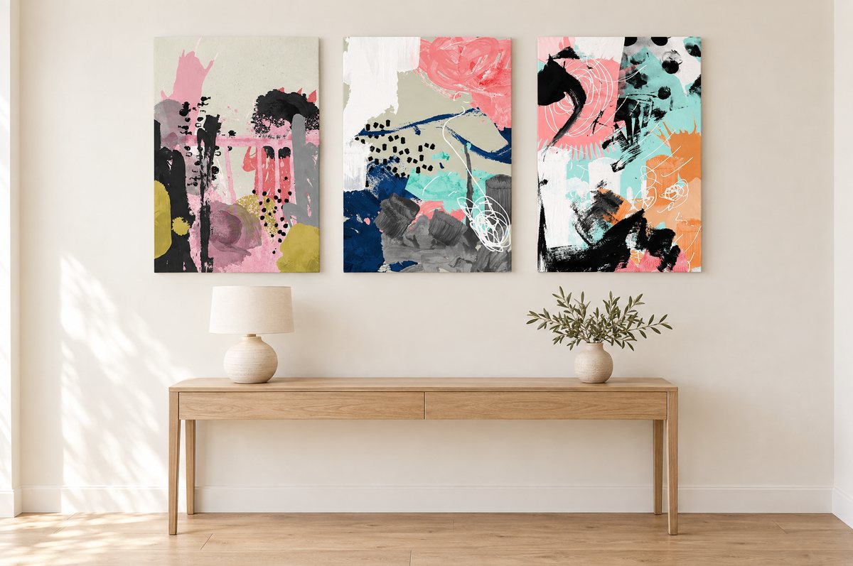 Three stretched canvases in a row above an oak console in a hallway